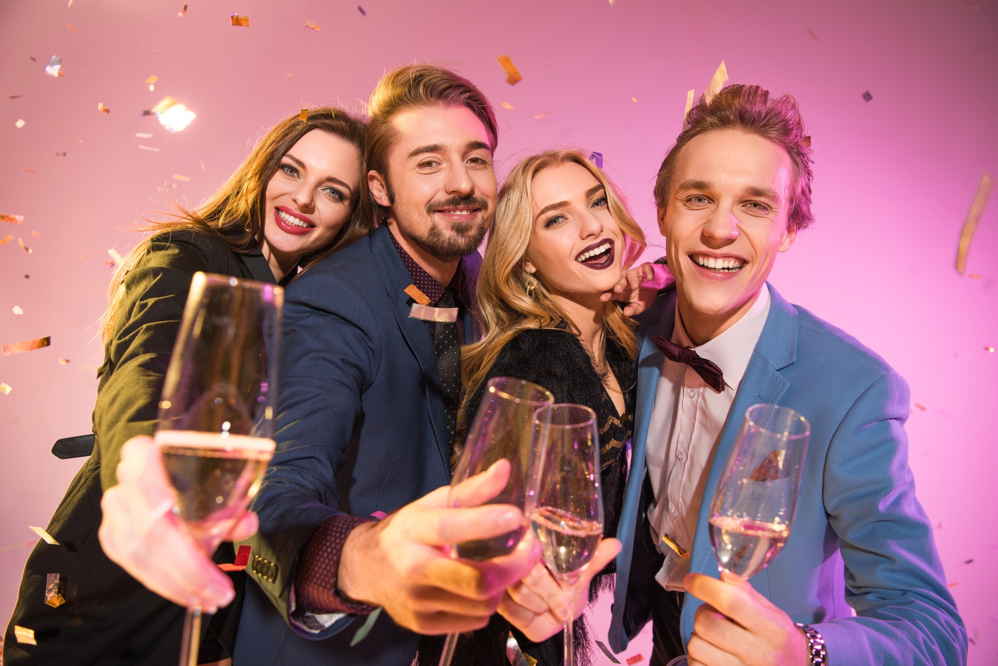 happy-friends-on-party-with-champagne-and-confetti-on-pink.jpg